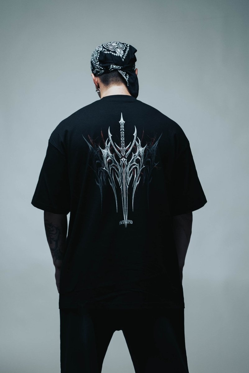 Person wearing a black t-shirt with a white graphic design on the back, standing against a gray background.