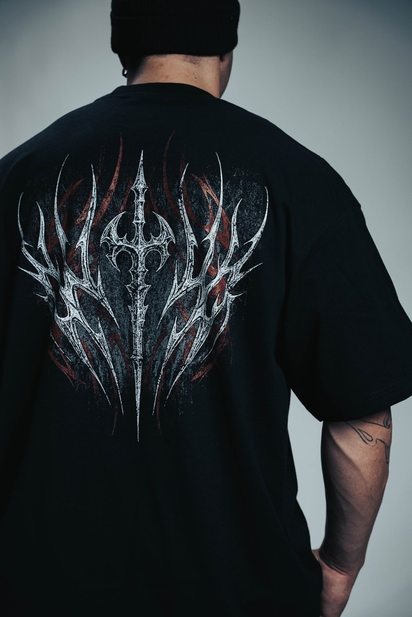 Person wearing a black t-shirt with a detailed design on the back against a gray background