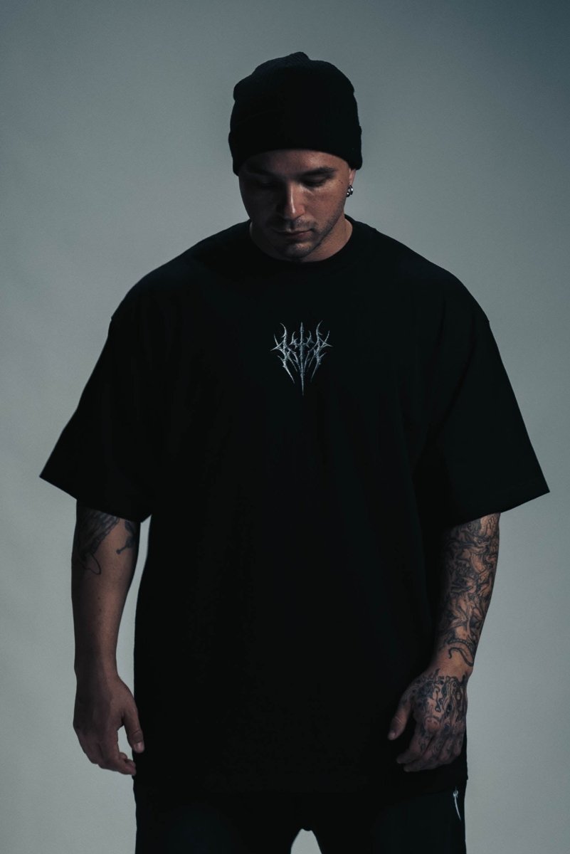 Person wearing a black t-shirt with a logo on a gray background
