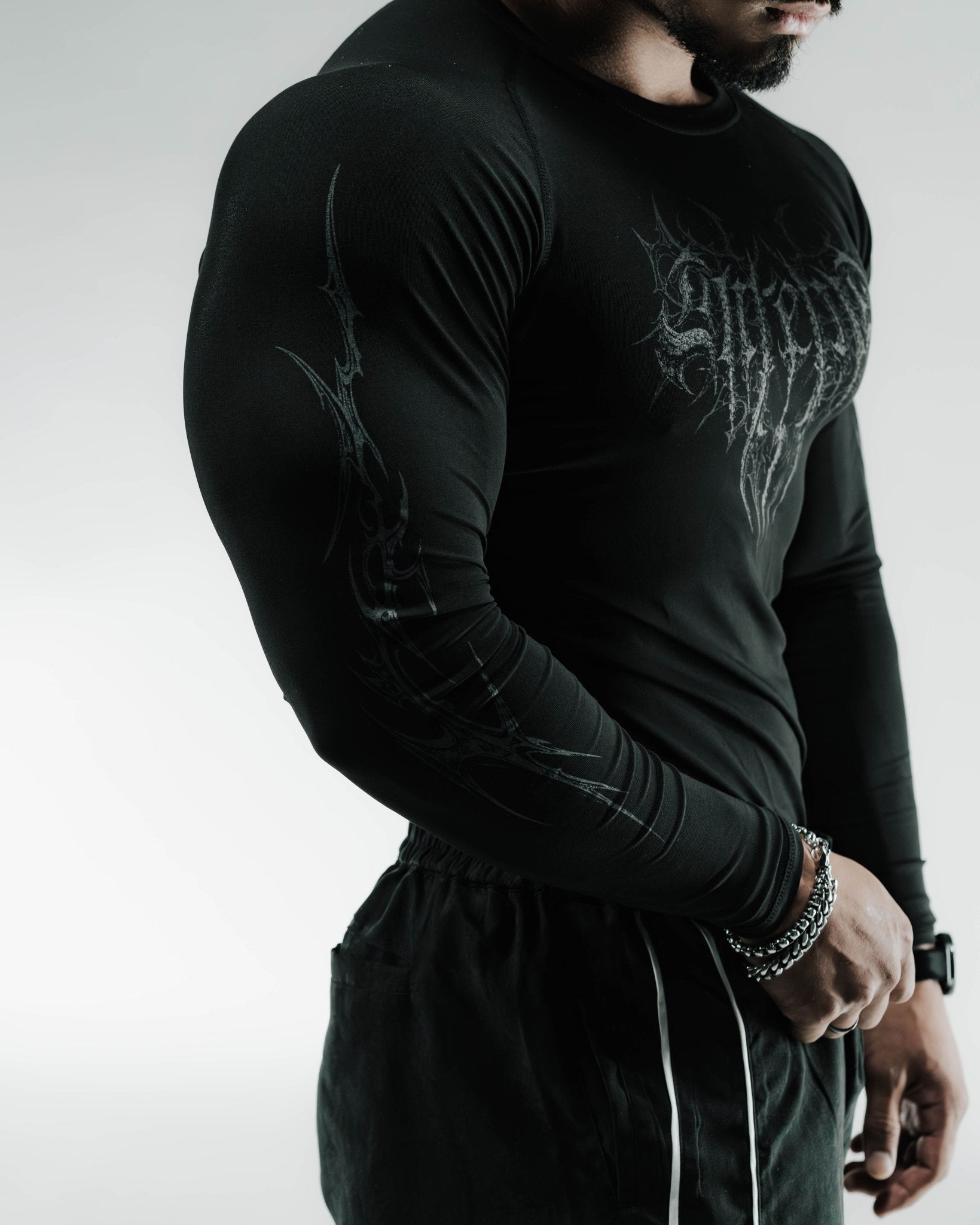 Person wearing a black long-sleeve shirt with graphic design on a plain background