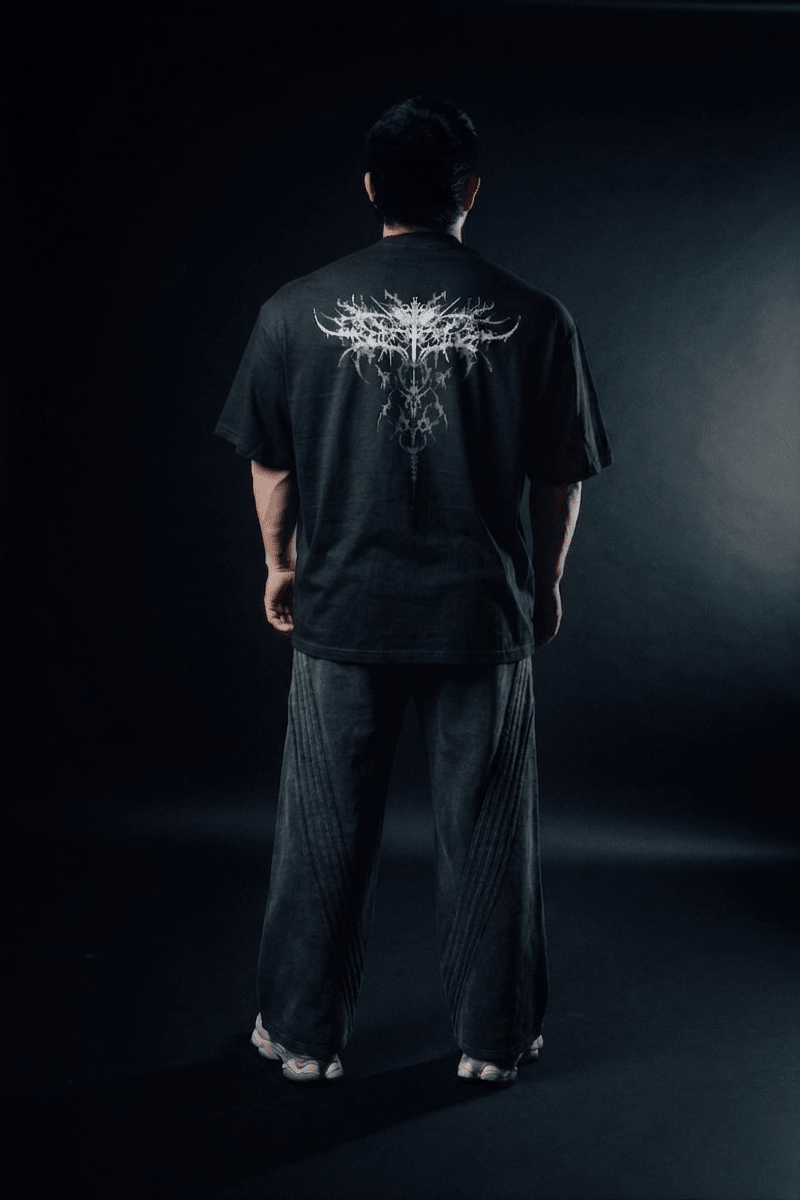 Person wearing a black t-shirt with a white graphic design on the back against a dark background