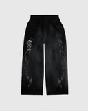 Black sweatpants with a flared open bottom and oversized screen print design in white, featuring a graphic that resembles a tribal or geometric pattern.