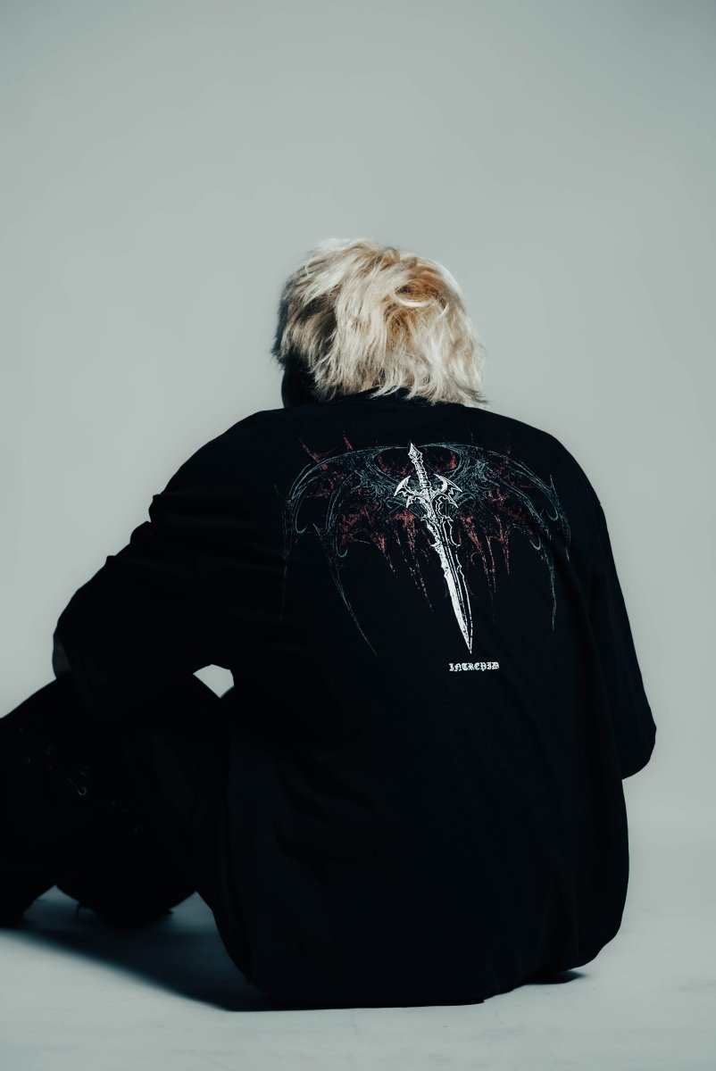 Person wearing a black jacket with a design on the back against a gray background
