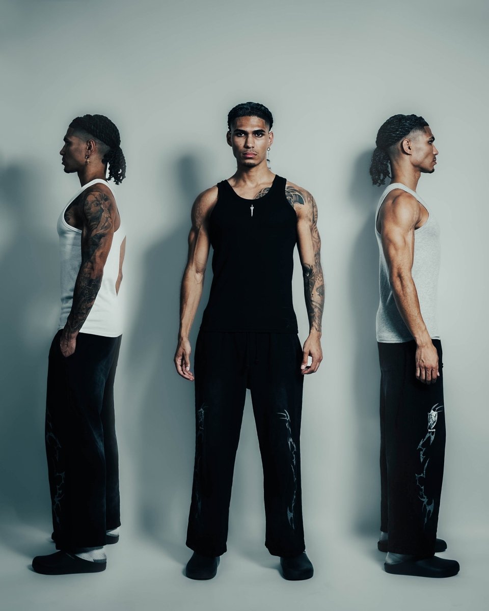 Three men wearing tank tops and pants against a plain background