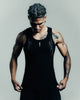 Man wearing a black tank top with tattoos on a gray background