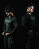 Two individuals wearing black long-sleeve shirts with graphic designs on a black background
