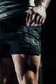 Person wearing black shorts with a white design on a dark background