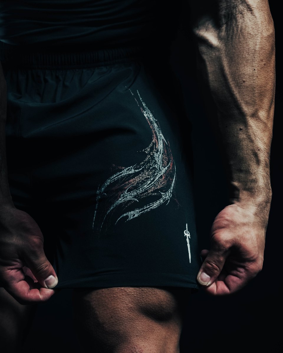 Person wearing black athletic shorts with a logo on a dark background