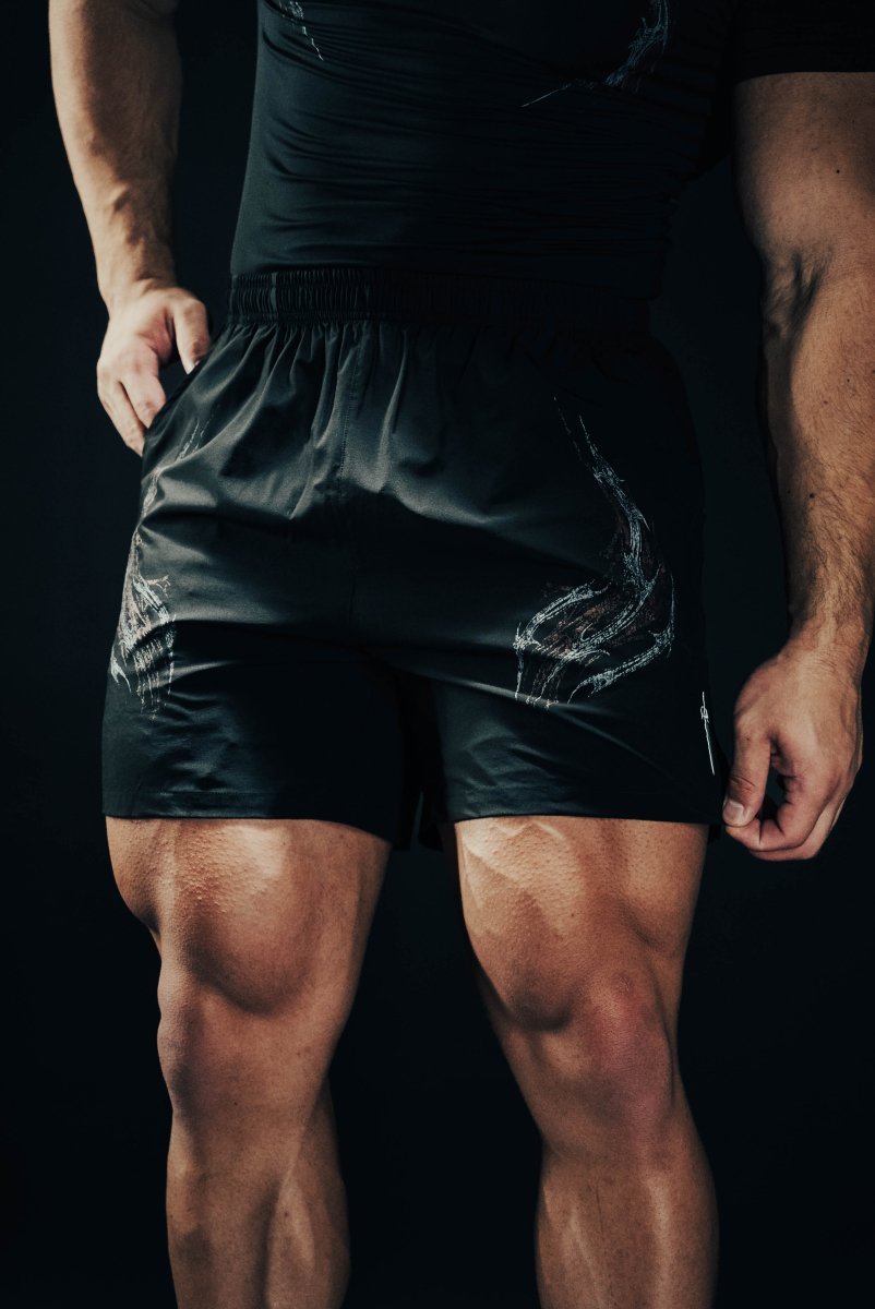 Person wearing black athletic shorts on a dark background