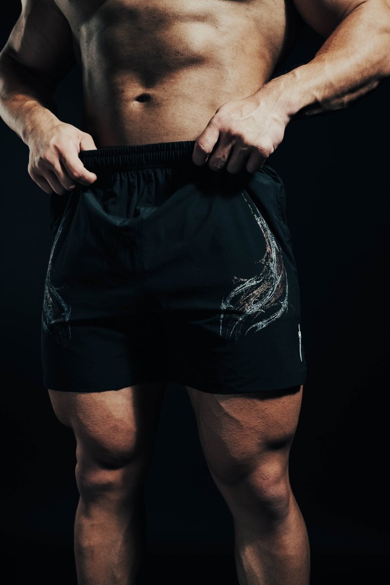 Person wearing black athletic shorts with a dark background