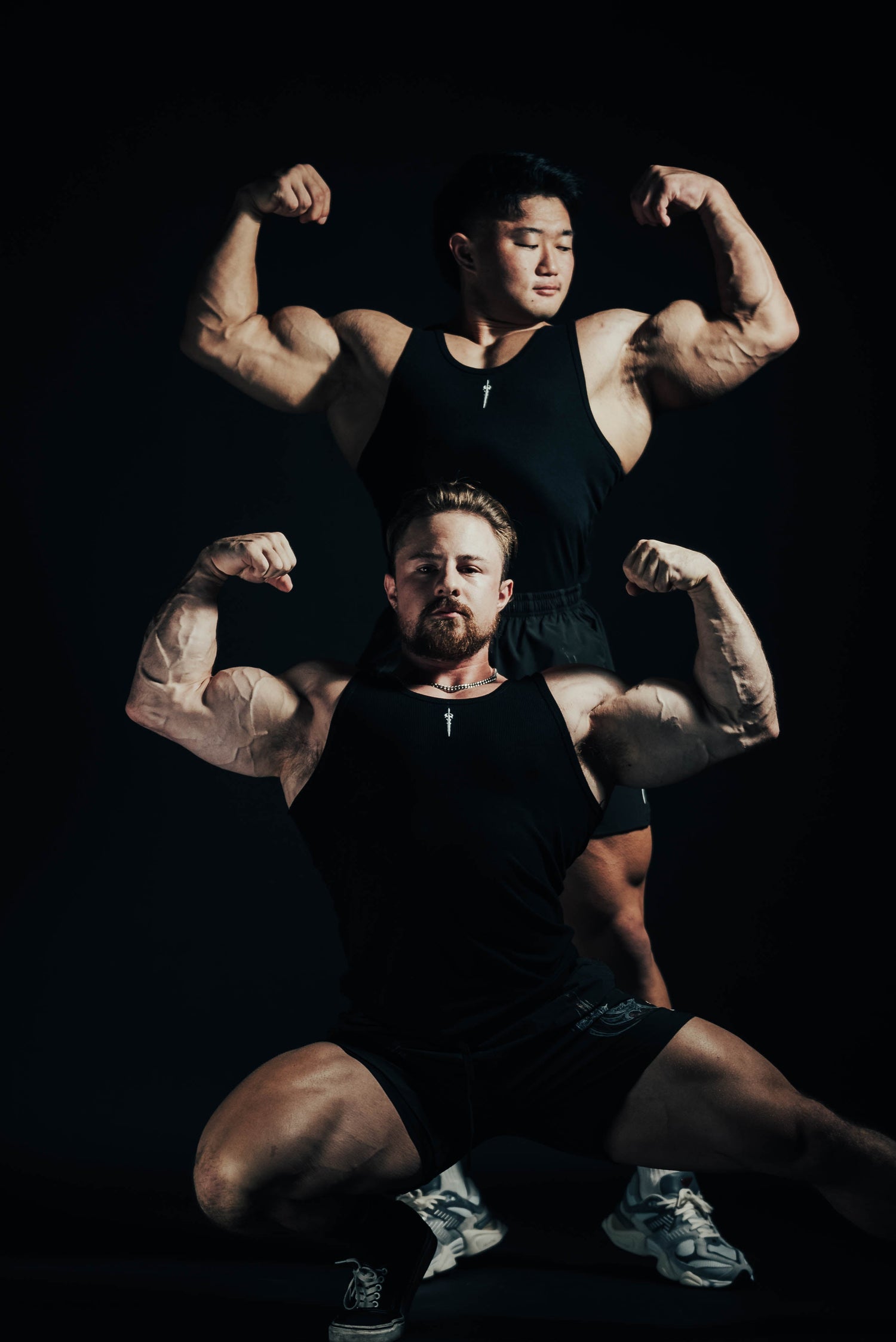 Two men flexing their muscles against a black background