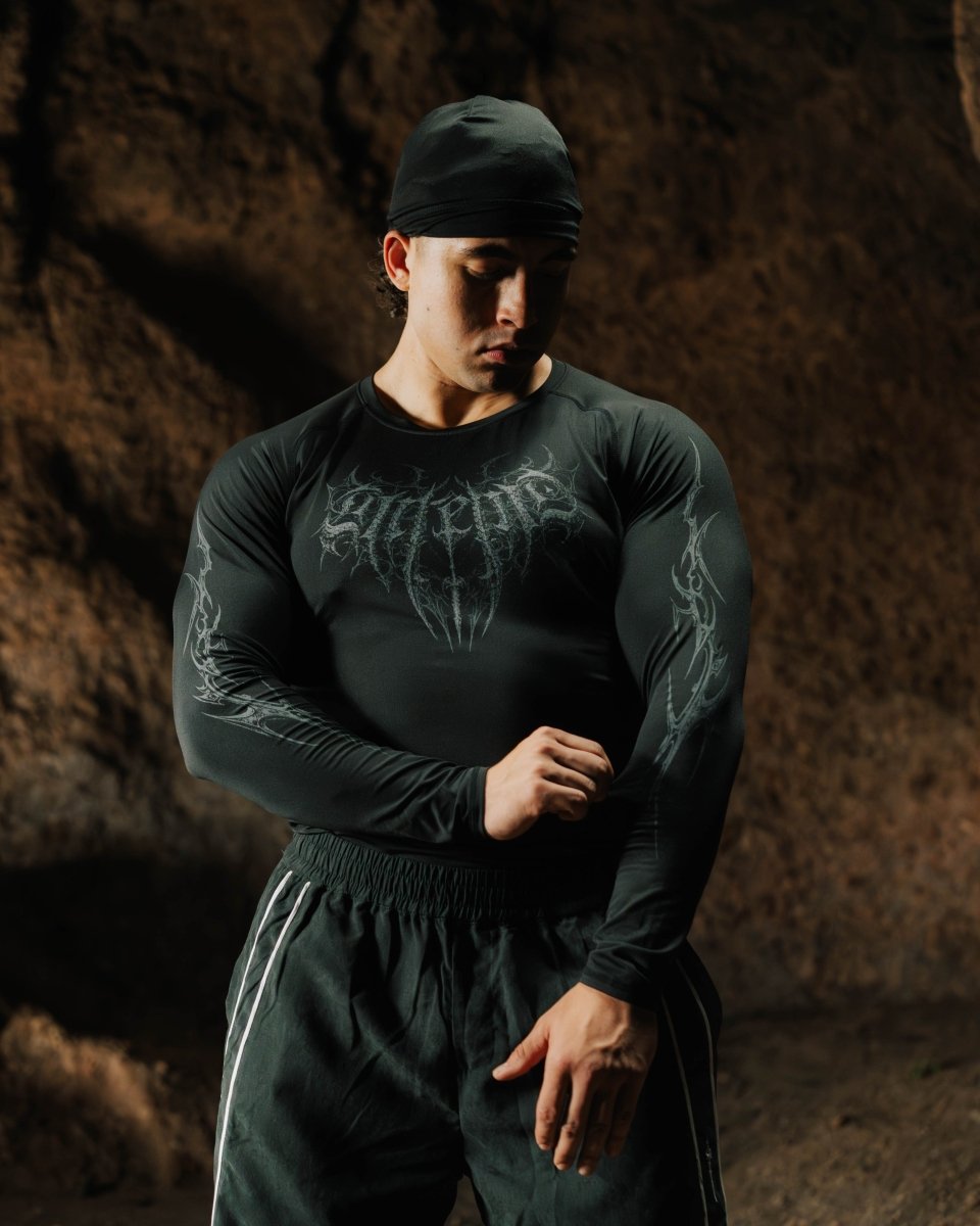 Person wearing a black long-sleeve shirt with graphic designs against a dark background