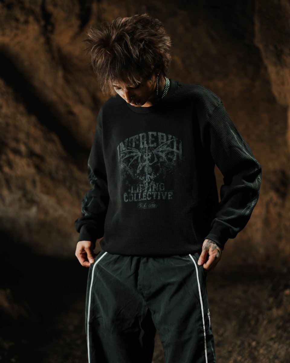 Person wearing a black sweatshirt with text and graphics against a dark background