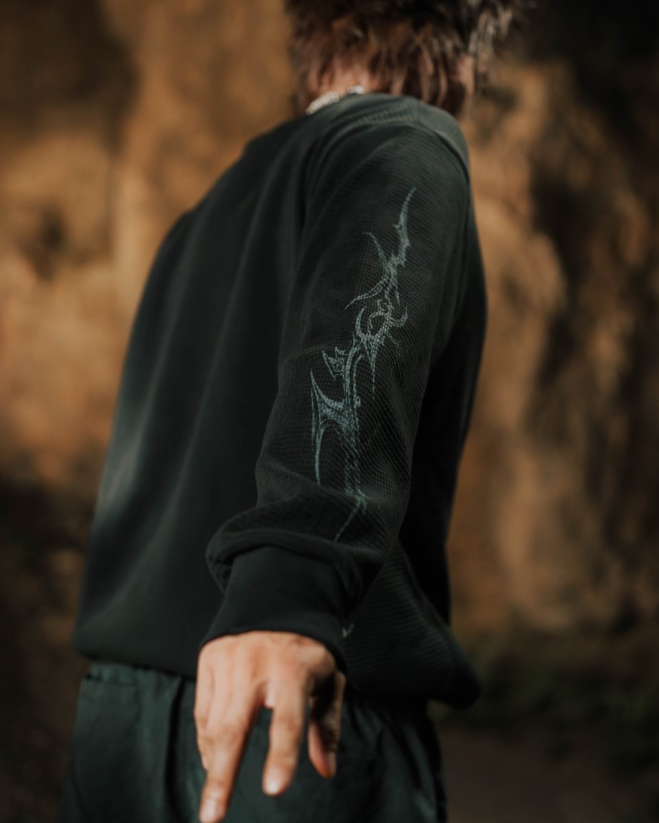 Person wearing a dark green sweatshirt with a dragon design outdoors