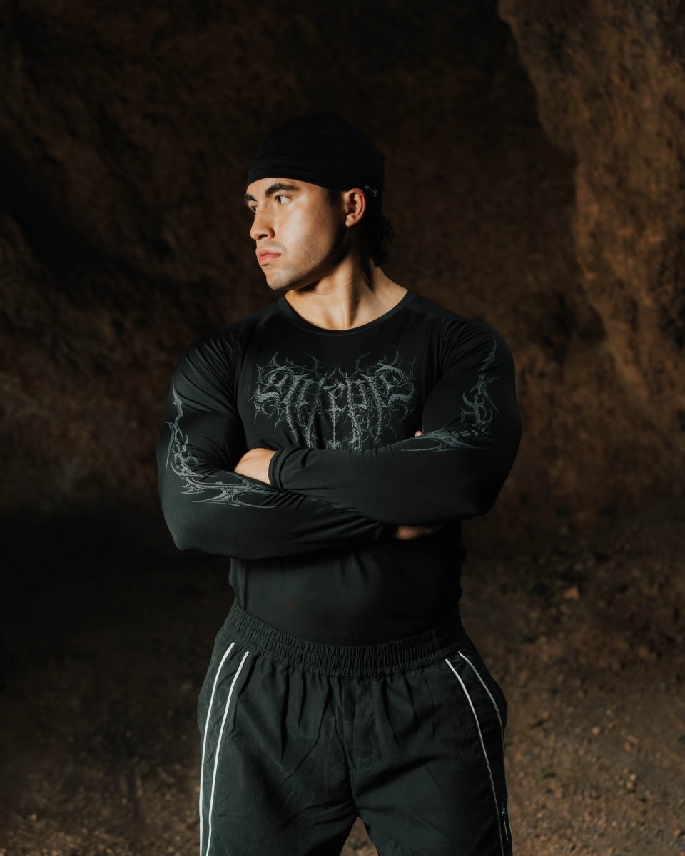 Man wearing a black long-sleeve shirt and pants with a dark background