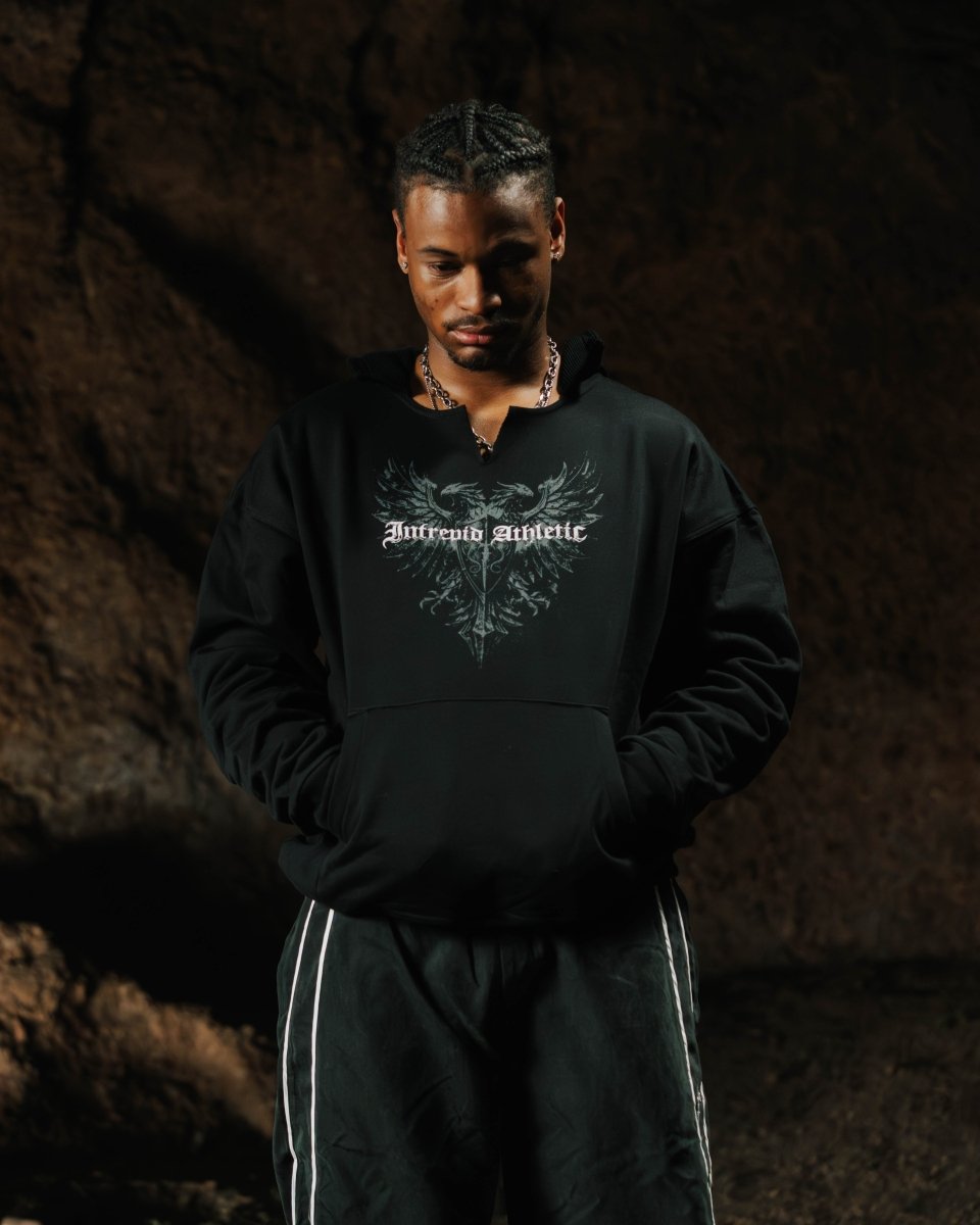 Person wearing a black hoodie with a logo on a dark background