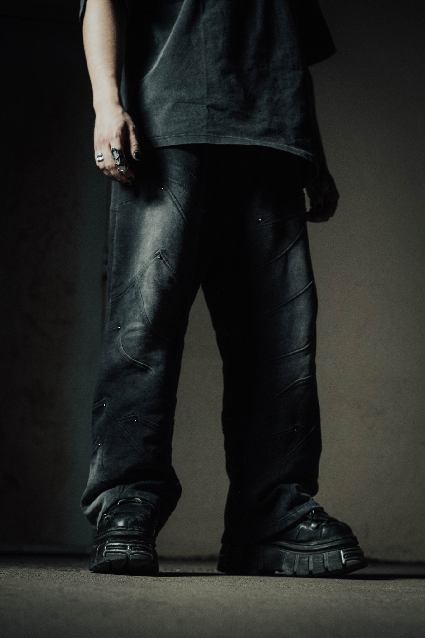 Person wearing dark jeans and black shoes against a plain background
