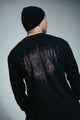 Person wearing a black long-sleeve shirt with red graphic design on the back against a gray background
