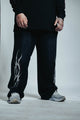 Person wearing black pants with white design and gray sneakers on a light background