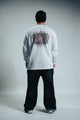 Person wearing a white long-sleeve shirt with a graphic design on the back against a gray background