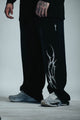 Black pants with white design worn by a person on a light gray background