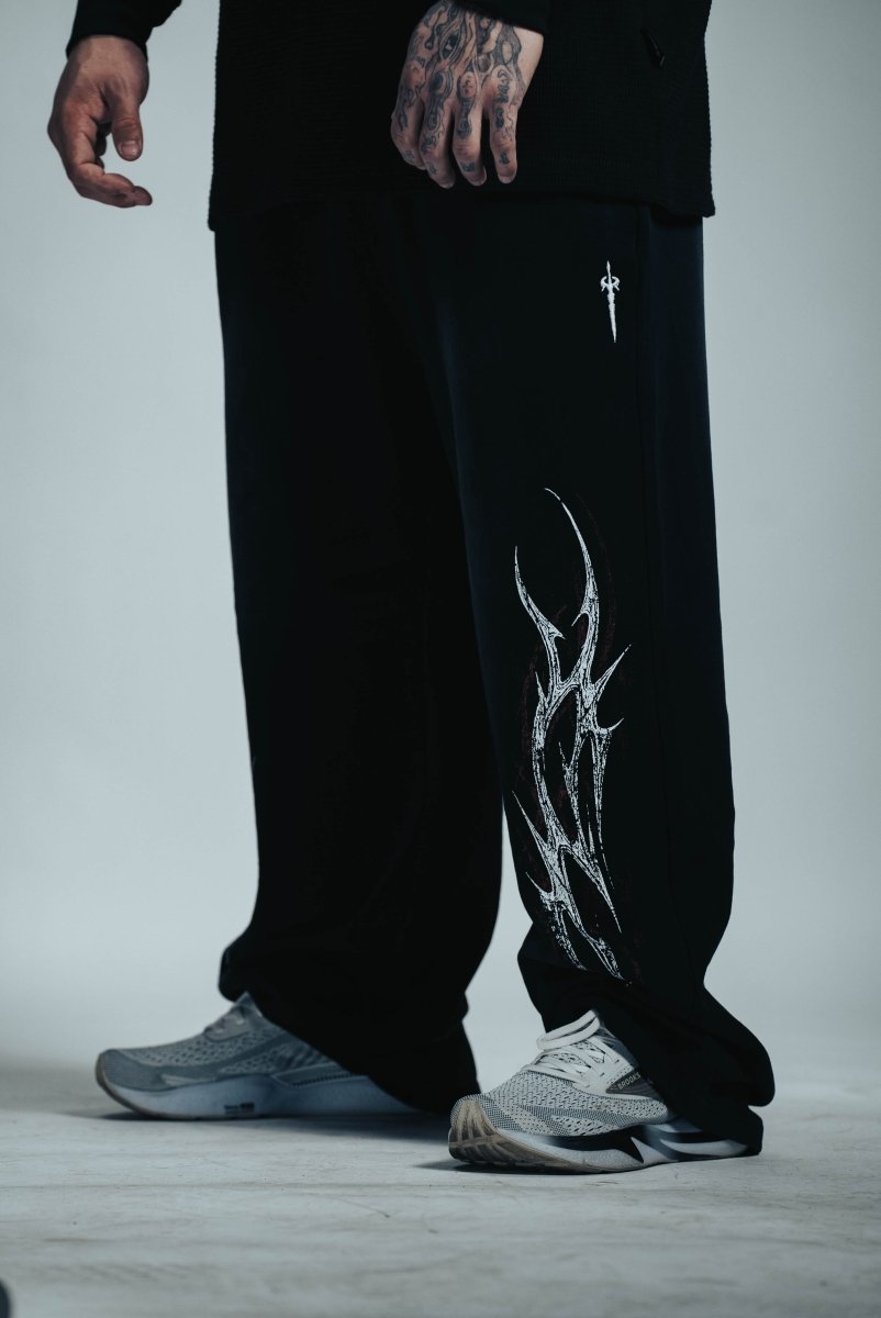 Black pants with white design worn by a person on a light gray background