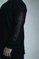Black long-sleeve shirt with intricate design on sleeve against a plain background