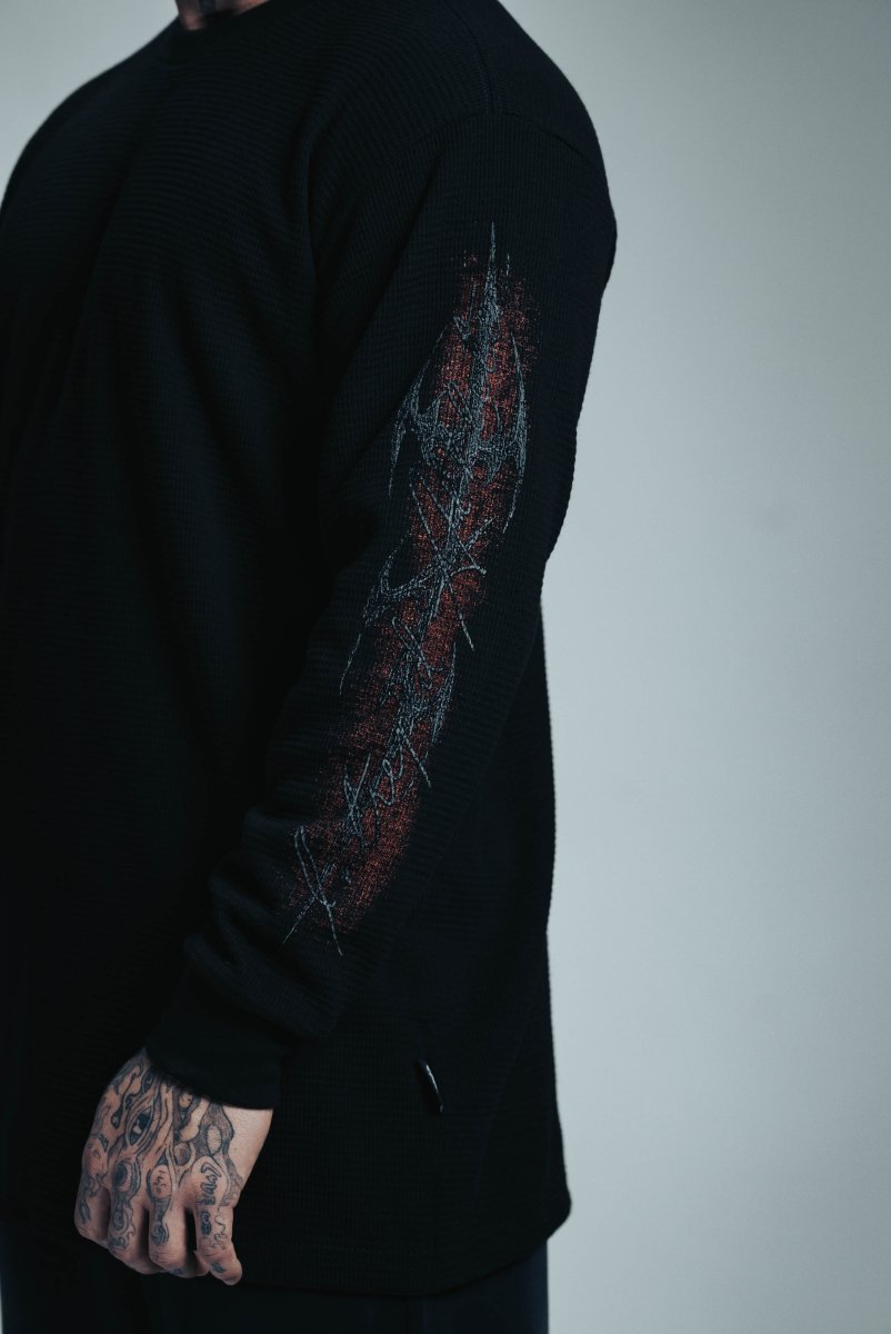 Black long-sleeve shirt with intricate design on sleeve against a plain background
