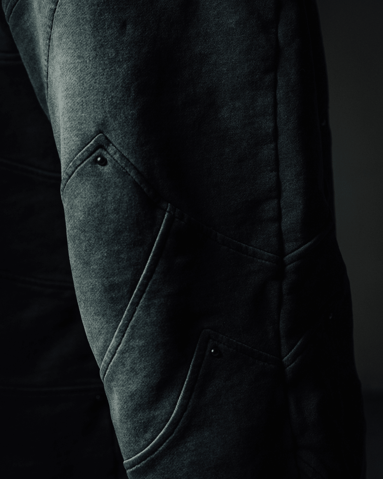 Close-up of dark gray pants with a blurred background