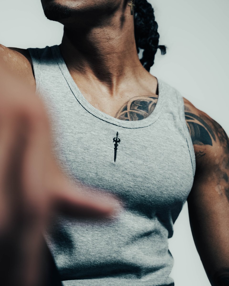 Person wearing a gray tank top with a small black design on a white background