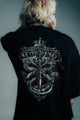 Person wearing a black shirt with a detailed design on the back against a gray background