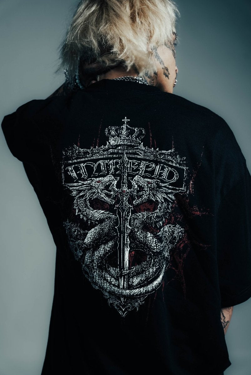 Person wearing a black shirt with a detailed design on the back against a gray background