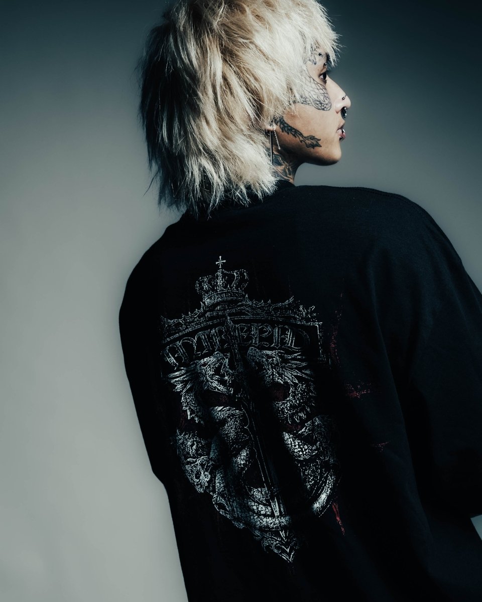 Person wearing a black jacket with intricate designs on the back against a gray background